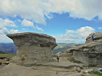 People on rock formation against sky