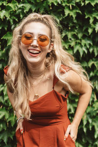 Portrait of smiling young woman wearing sunglasses standing outdoors