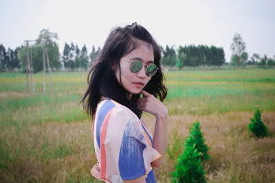 Young woman wearing sunglasses standing on field