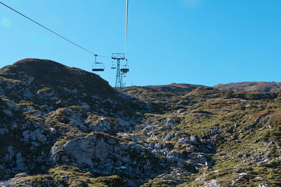 Overhead cable car over mountains against sky