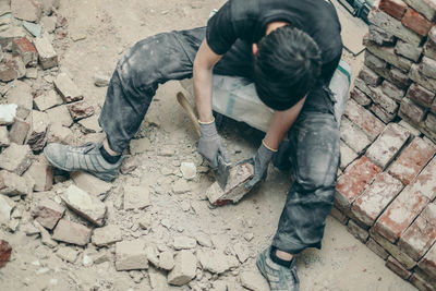 A young man cleans bricks with an axe.