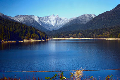 Scenic view of lake and mountains against clear blue sky