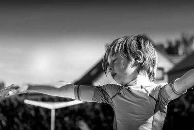 Rear view of boy with arms outstretched standing outdoors