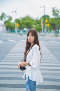 Portrait of woman standing on road in city