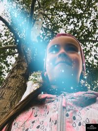 Low angle view of boy on tree trunk