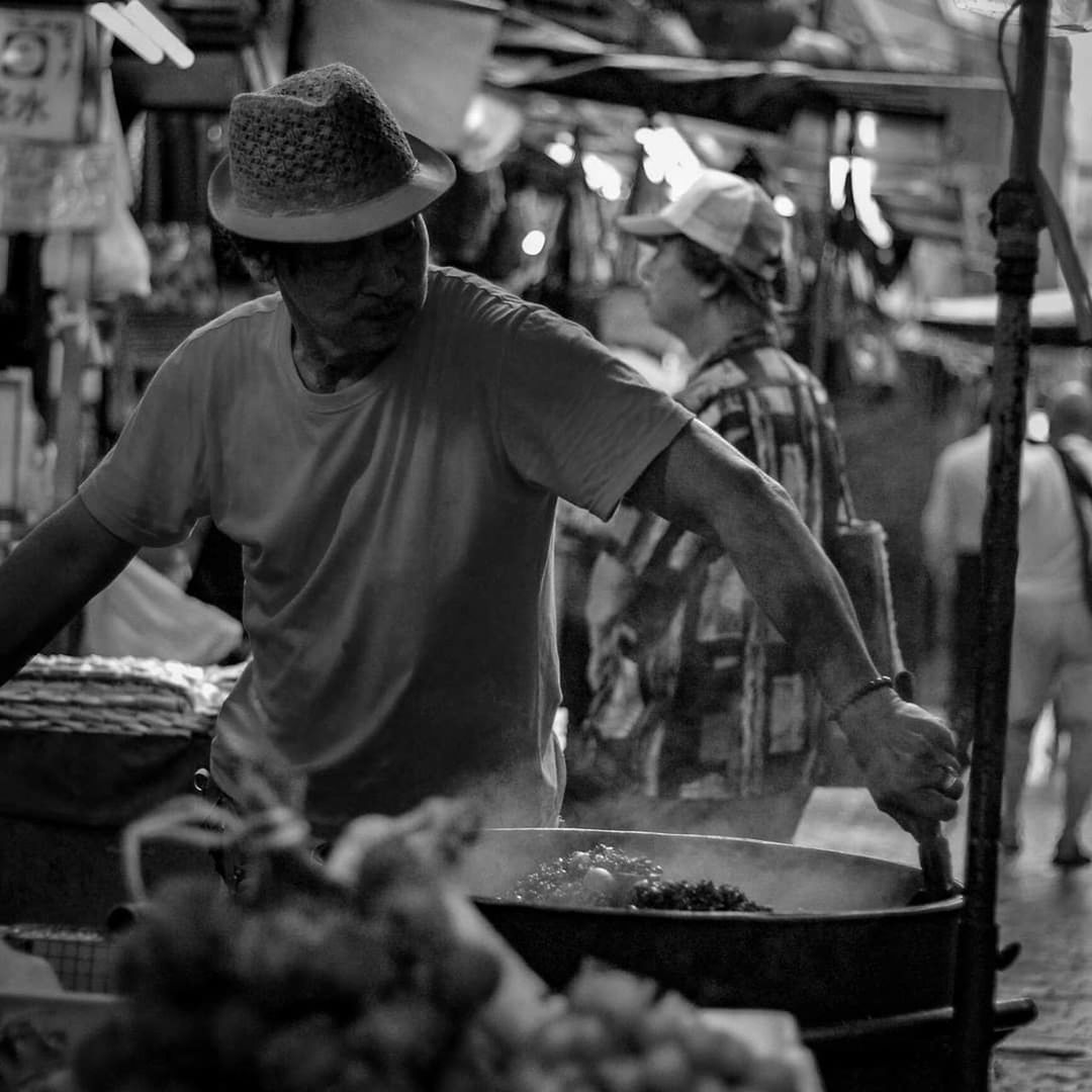 one person, market, occupation, adult, real people, hat, working, men, market stall, day, waist up, retail, three quarter length, business, food, clothing, preparation, standing, casual clothing