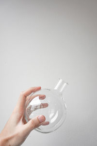 Close-up of hand holding glass against white background