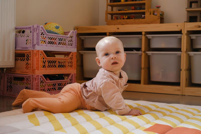 Infant on the floor of kids play room learning to crawl on the rug. early development. baby girl on