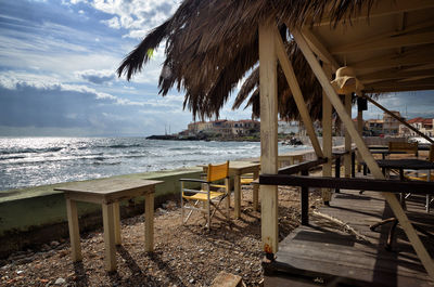 Chairs and table on beach against sky