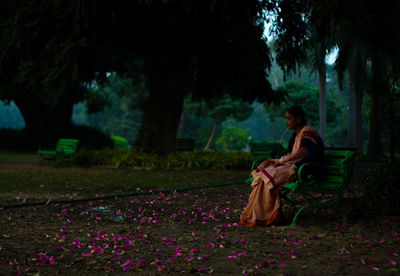 Woman in sari sitting on bench at park