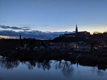 Reflection of illuminated buildings in river against sky