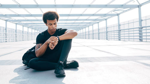 Young man sitting on bridge