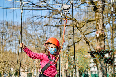 Low angle view of woman standing on chainlink fence