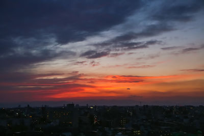 Cityscape against dramatic sky during sunset