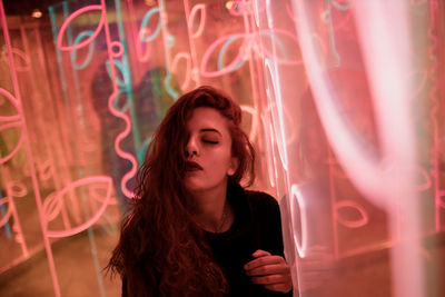 Beautiful young woman standing against illuminated lights