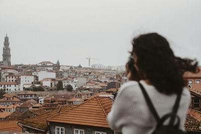 Rear view of woman looking at city against sky