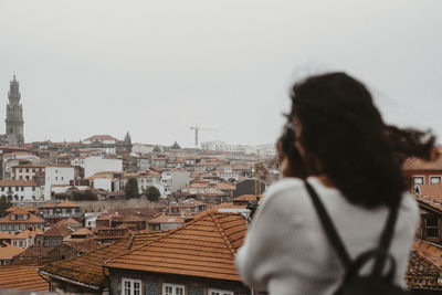 Rear view of young woman with backpack photographing cityscape against sky