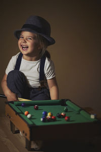 Charming child in retro clothes playing toy billiards.