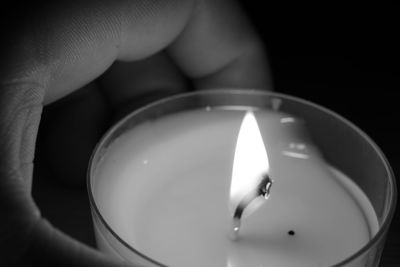 Close-up of hand holding lit candle