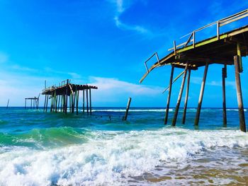 Broken pier in sea against sky