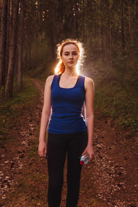 Portrait of young woman standing in forest