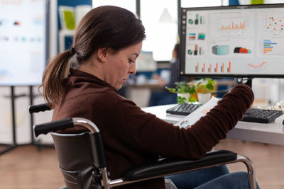 Side view of young woman using mobile phone in cafe