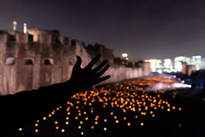 Midsection of person against illuminated buildings in city at night