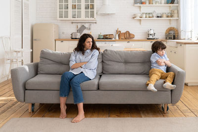 Full length of woman sitting on sofa at home