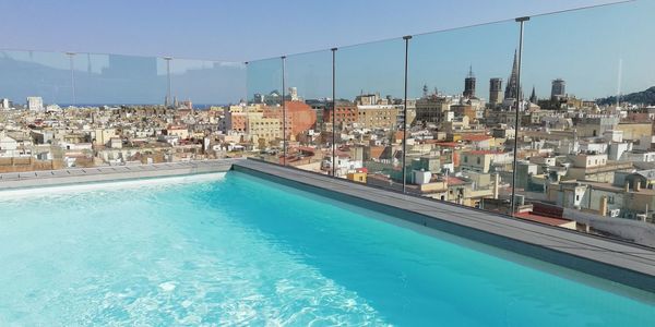 Swimming pool by buildings against clear blue sky