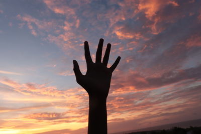 Low angle view of silhouette hand against orange sky