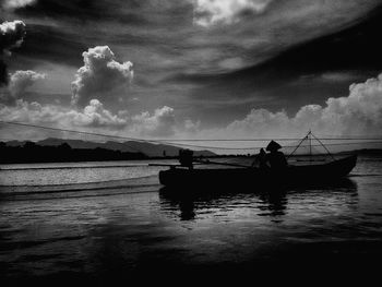 Boats in sea against cloudy sky