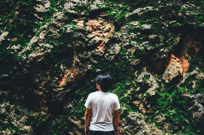 Rear view of man standing by trees in forest