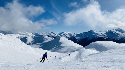 People skiing on snowcapped mountain against sky