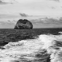 Rock formation in sea against sky