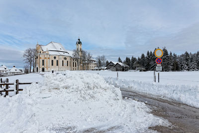 Empty road amidst snow covered field leading towards wies church at winter