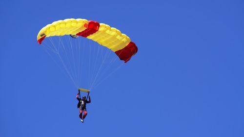 Low angle view of person paragliding against clear blue sky