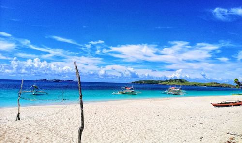 Sailboats moored on beach against sky