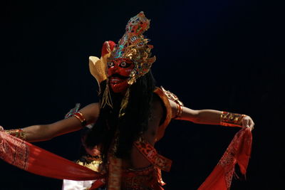 Man wearing costume performing against black background