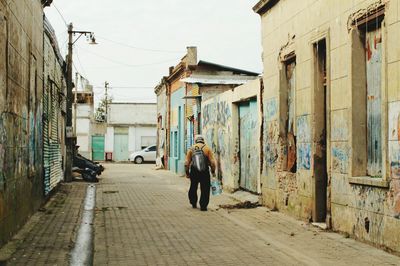 Rear view of man walking on cobblestone street