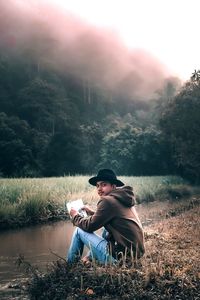 Young man sitting on land in forest