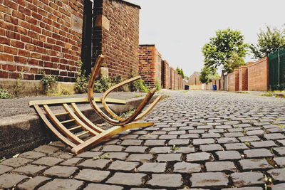 Cobblestone street amidst trees against sky