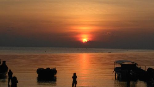 Silhouette man standing on beach against sky during sunset