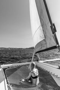 Rear view of woman in boat sailing on sea against sky