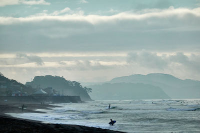 Scenic view of sea and beach against sky in foggy morning