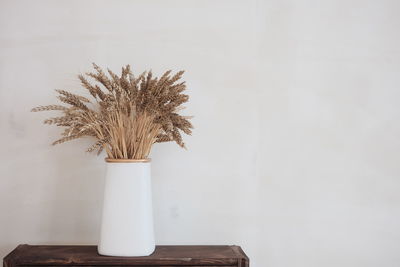 Close-up of white vase on table against wall