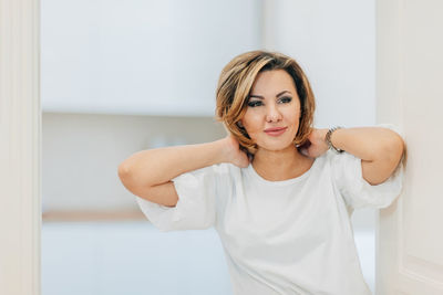 A beautiful woman in a white t-shirt preens for a date, straightens her hair, hair. mock-up. closeup