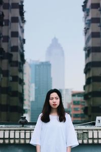 Portrait of smiling young woman standing against buildings