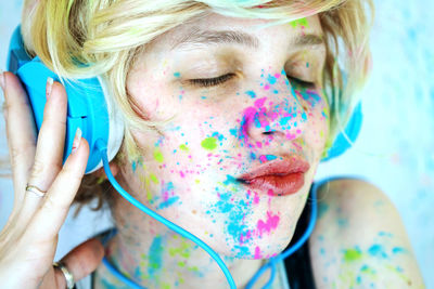 Close-up of woman with powder paint on her face listening music