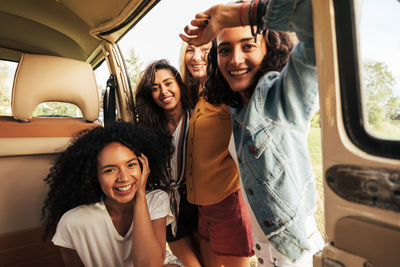 Portrait of smiling friends near camping van