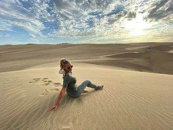 Woman sitting at desert during sunset